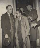 Herschel Grynszpan entouré de policiers sortant de son premier interrogatoire dans les locaux de la Police Judiciaire. Paris, France, 7 novembre 1938.